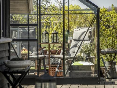 a glass house with a chair on a patio at Holiday Home Ylvie - 150m from the sea by Interhome in Frørup