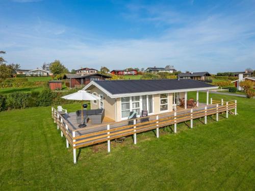 a house with a large wooden deck in a field at Holiday Home Arton - 300m from the sea by Interhome in Ebberup