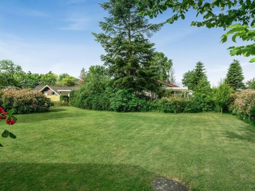 a yard with a large tree and a house at Holiday Home Juditha - 400m from the sea by Interhome in Middelfart