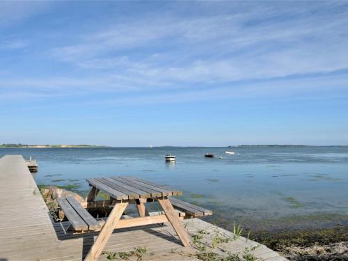 a wooden picnic table sitting on top of a body of water at Holiday Home Chayton - 450m from the sea by Interhome in Fåborg
