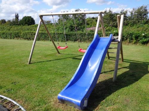 a playground with a blue slide in a yard at Holiday Home Dunya - 400m from the sea by Interhome in Assens
