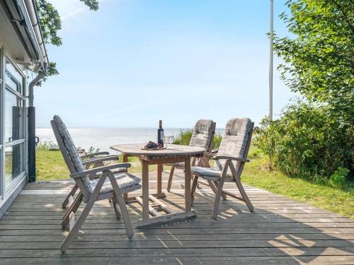 a table with three chairs and a bottle of wine at Holiday Home Selja - 15m from the sea by Interhome in Oure
