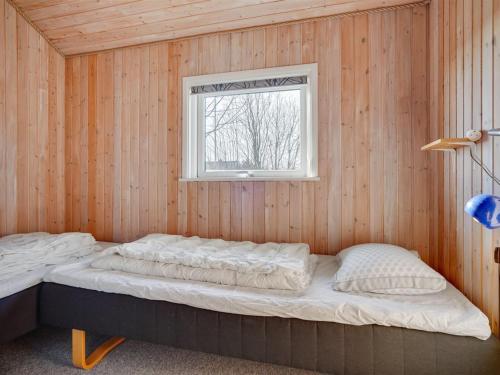 a bed in a wooden room with a window at Holiday Home Dunya - 400m from the sea by Interhome in Assens