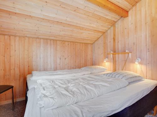 a large white bed in a wooden room at Holiday Home Dunya - 400m from the sea by Interhome in Assens