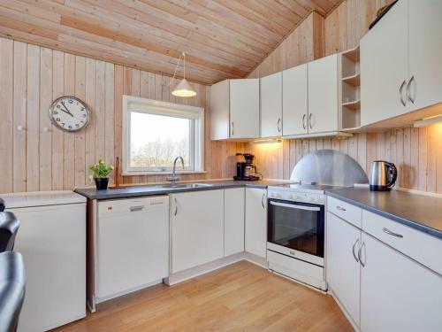 a kitchen with white cabinets and a clock on the wall at Holiday Home Dunya - 400m from the sea by Interhome in Assens