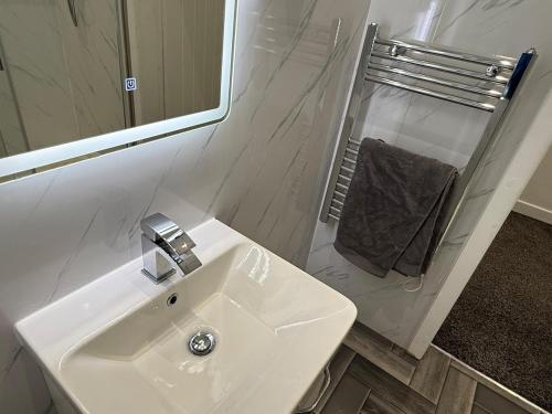 a white bathroom with a sink and a mirror at Pendle view- luxurious Studio in Brierfield