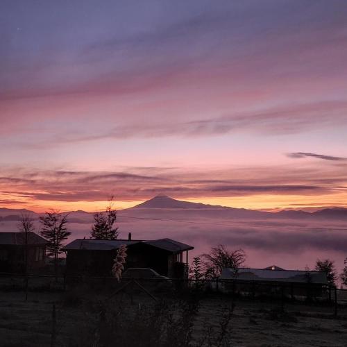 a sunset with a view of a mountain with clouds at Centro Turístico Epu Pillan Domo in Panguipulli