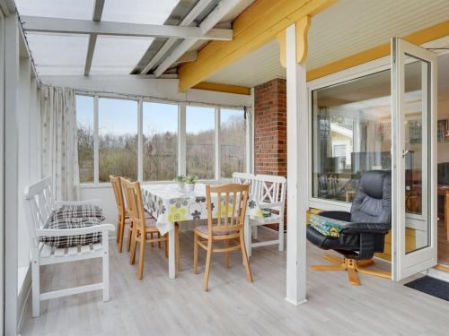 a dining room with a table and chairs on a porch at Holiday Home Hejne - 29km from the sea by Interhome in Toftlund