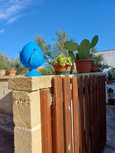 a blue statue on a fence with potted plants at Trullo Salento a 2 passi dal mare - Apulia Home in Capilungo