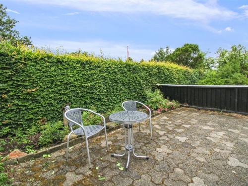 two chairs and a table in front of a hedge at Holiday Home Siouxsie - 500m from the sea by Interhome in Esbjerg