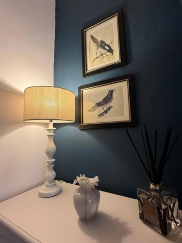 a table with a lamp and two pictures on a wall at The Whitchurch Apartment- The Painted Rooms in Whitchurch