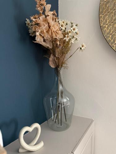 a vase with flowers in it on a table at The Whitchurch Apartment- The Painted Rooms in Whitchurch