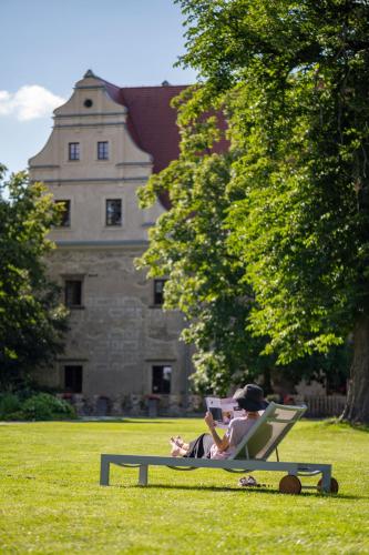 a man sitting in a lawn chair reading a book at Uroczysko Siedmiu Stawów Spa by L'Occitane in Gola Dzierżoniowska