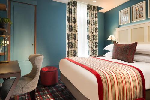a hotel room with a bed and a desk and a chair at Les Tournelles in Paris