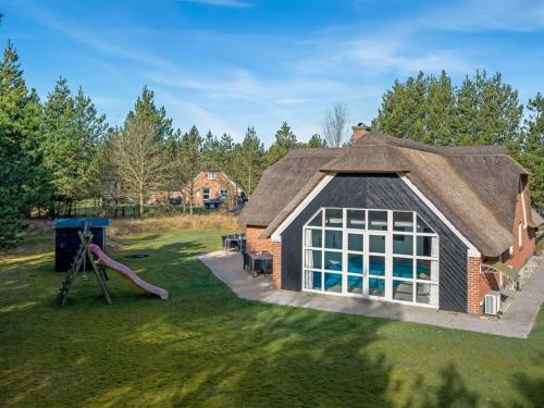 a house with a thatched roof and a playground at Holiday Home Dorris - 4-3km from the sea by Interhome in Nørre Nebel