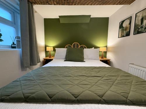 a bedroom with a large bed with a green wall at The Whitchurch Apartment- The Painted Rooms in Whitchurch