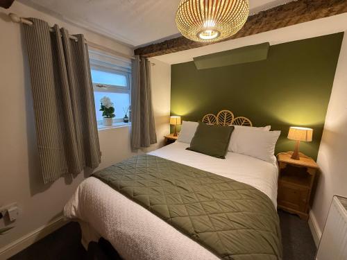 a bedroom with a bed with a green headboard and a window at The Whitchurch Apartment- The Painted Rooms in Whitchurch