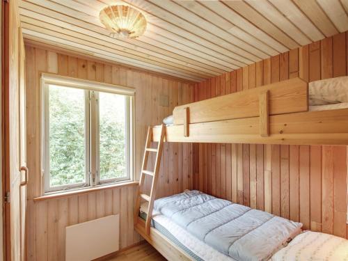 a bunk bed in a wooden room with a ladder at Holiday Home Jaane - 650m to the inlet by Interhome in Hemmet