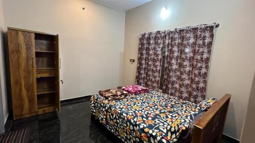 a bedroom with a bed and a curtain and a cabinet at Garden Homestay in Yelagiri