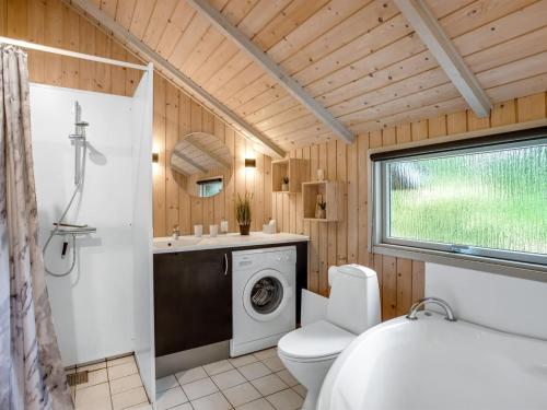 a bathroom with a toilet and a washing machine at Holiday Home Tecla - 12km from the sea by Interhome in Oksbøl