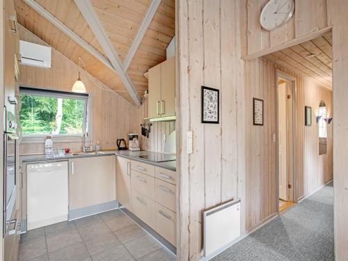 a kitchen with wooden walls and a clock on the wall at Holiday Home Tecla - 12km from the sea by Interhome in Oksbøl