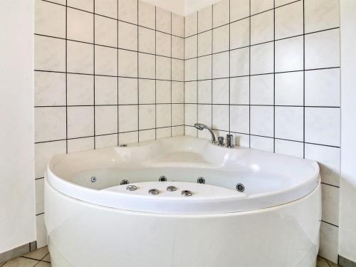 a white bath tub in a white tiled bathroom at Holiday Home Jani - 25km from the sea by Interhome in Toftlund