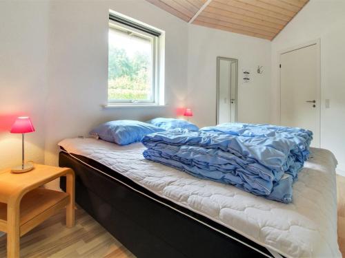 a bedroom with a bed with blue comforter and a window at Holiday Home Jani - 25km from the sea by Interhome in Toftlund