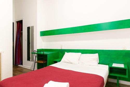 a bedroom with a bed with a red and green headboard at Hôtel De La Gare Nantes Station Hotel Nantes in Nantes