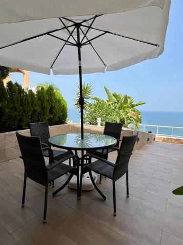 a table and chairs with an umbrella on a patio at Roger's house frente al mar en Alicante in Gran Alacant
