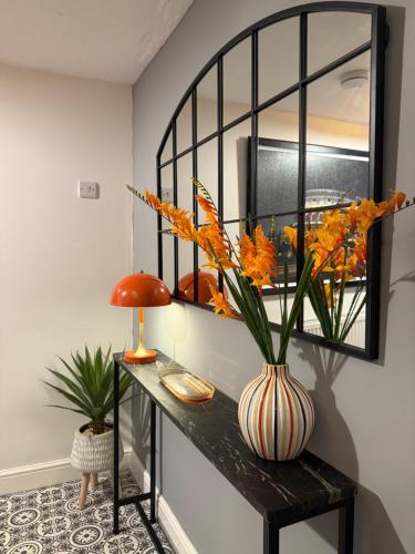 a room with a table with a vase of flowers on it at The Whitchurch Apartment- The Painted Rooms in Whitchurch