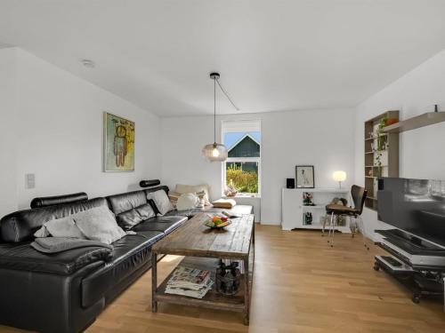 a living room with a black couch and a table at Holiday Home Aleida - 100m to the inlet by Interhome in Vemb