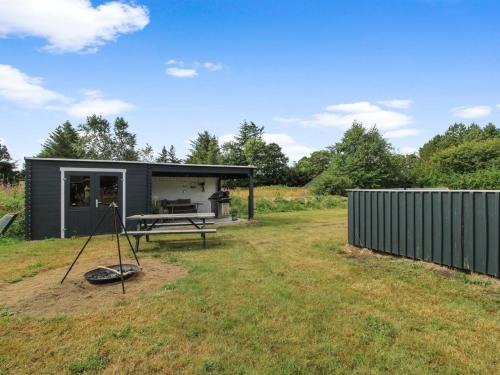 a black tiny house with a picnic table in a yard at Holiday Home Daina - 400m to the fjord by Interhome in Vemb
