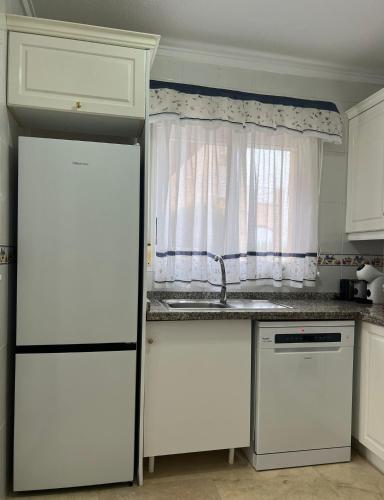 a kitchen with a white refrigerator and a window at Roger's house frente al mar en Alicante in Gran Alacant