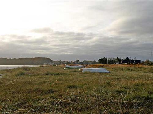 a boat sitting in a field next to a body of water at Holiday Home Emmik - 150m from the sea by Interhome in Børkop