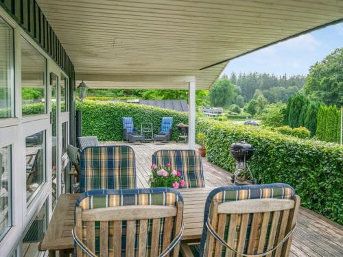a porch with four chairs and a table with flowers at Holiday Home Algot - 100m to the inlet by Interhome in Børkop