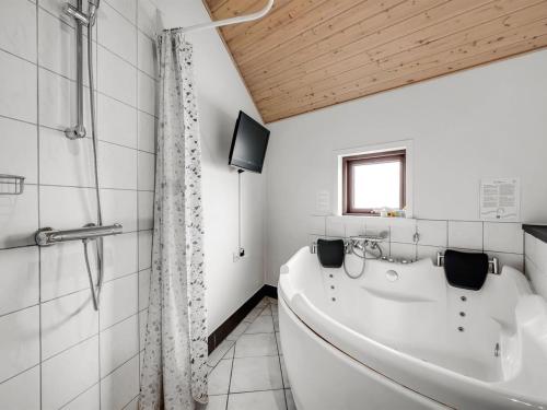 a white bathroom with a tub and a shower at Holiday Home Reiner - 300m to the fjord by Interhome in Skjern
