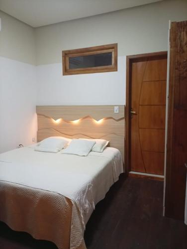 a bedroom with a large white bed with lights on it at chale comandatuba in Água Boa