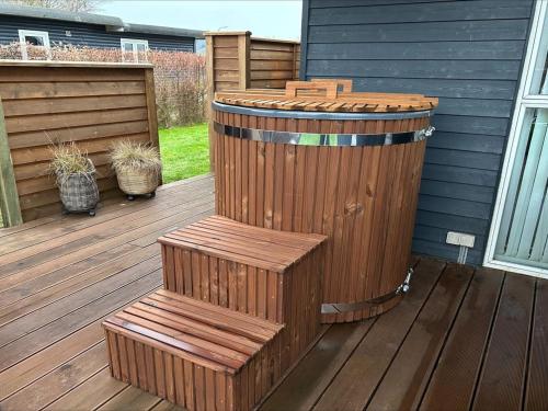 a wooden deck with a wooden barrel and a bench at Holiday Home Nine - 200m from the sea by Interhome in Børkop