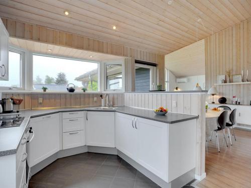 a kitchen with white cabinets and a large window at Holiday Home Nine - 200m from the sea by Interhome in Børkop