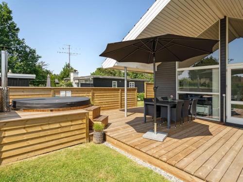 a wooden deck with a table and an umbrella at Holiday Home Nine - 200m from the sea by Interhome in Børkop