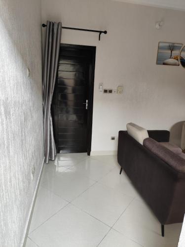 a living room with a couch and a black door at SIKA Résidences BJ in Cocotomey