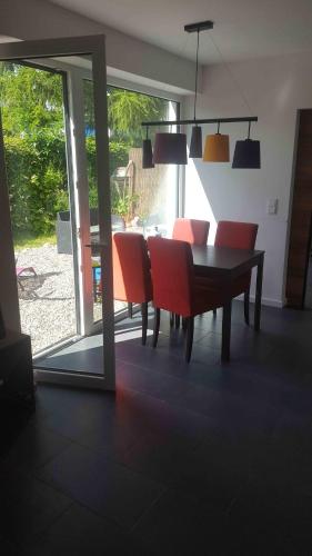 a dining room with a table and red chairs at Spatzenhecke in Klütz