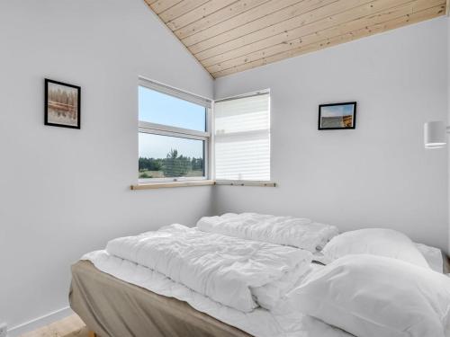 a bedroom with white walls and a bed with pillows at Holiday Home Sulki - 3-5km from the sea by Interhome in Frøstrup