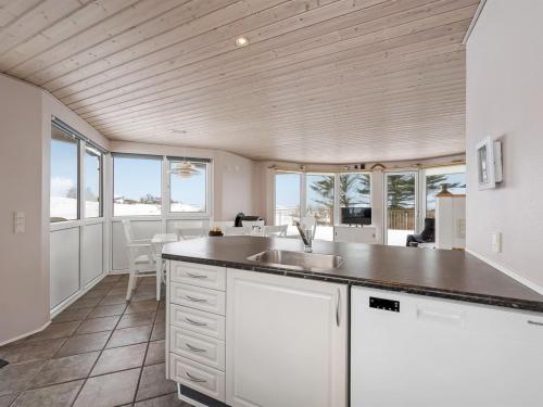 a kitchen with white cabinets and a sink and windows at Holiday Home Ginny - 300m to the fjord by Interhome in Struer
