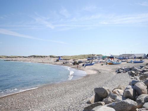 a beach with rocks and the water and people on it at Holiday Home Biriel - 1km from the sea by Interhome in Thisted