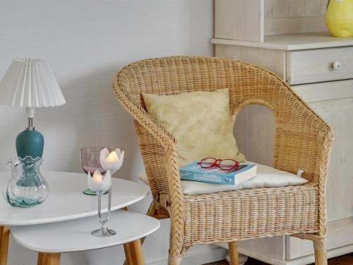 a wicker chair with a book and glasses on a table at Apartment Gerwendil - 500m to the fjord by Interhome in Øsløs