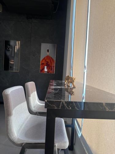 a dining room table with white chairs and a black counter top at Private Villa for rent in Māḩiş