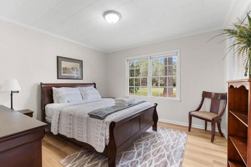 a bedroom with a bed and a chair and a window at Southern haven on granade - family retreat in Statesboro
