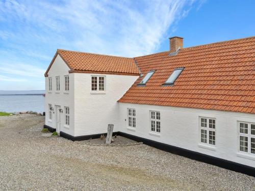 a white house with an orange roof next to the water at Holiday Home Thorge - 75m to the inlet by Interhome in Struer