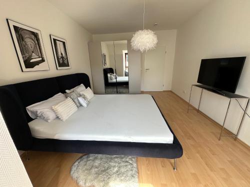 a bedroom with a large white bed and a flat screen tv at 2 Zi Wohnung, zentrale Lage mit Parkplatz, 15 min vom Hbf Hamburg in Pinneberg